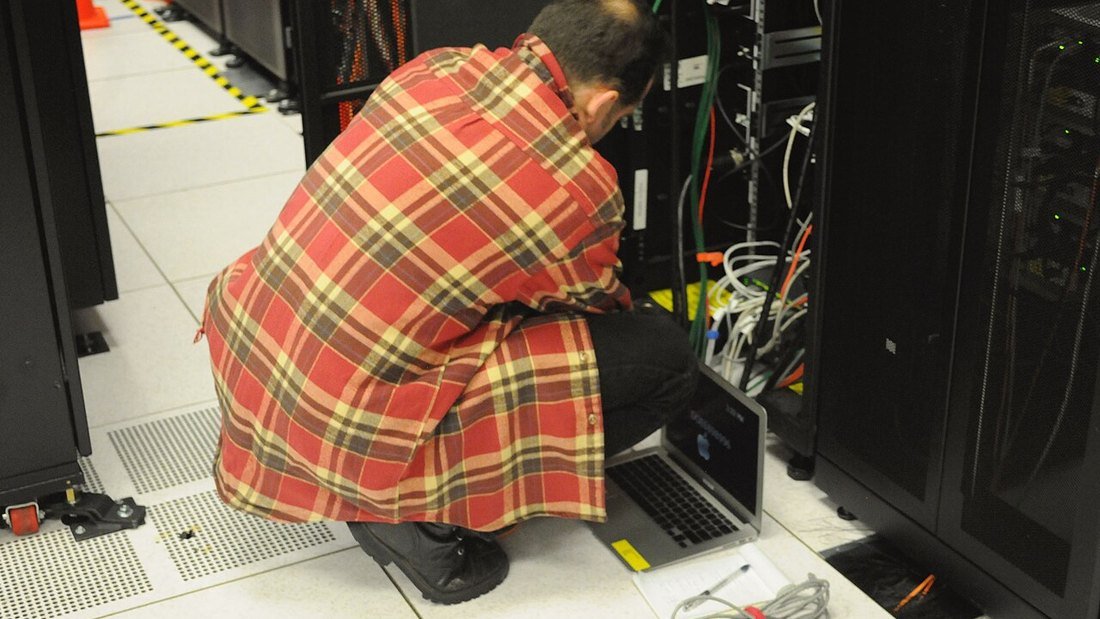 Technician working on a server rack in a data centre cold aisle