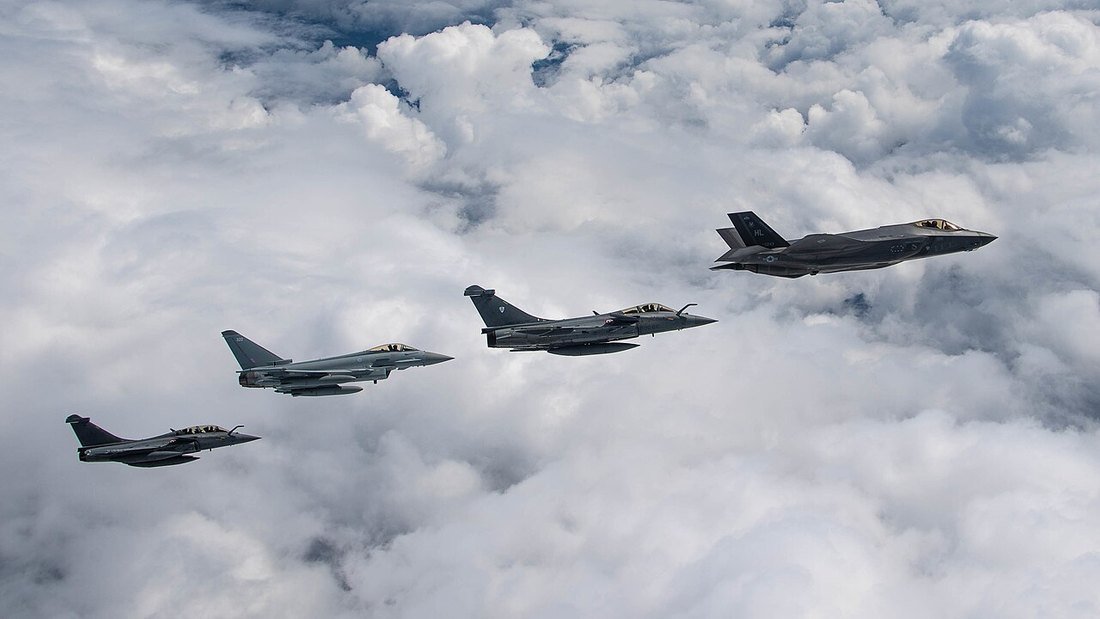French Rafale, RAF Typhoon and US Air Force F-35A fighters flying in formation above cloud